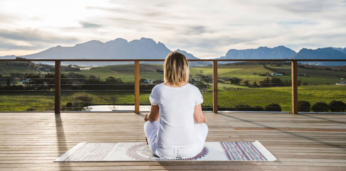 Image of woman in seated yoga pose with a view of the Cape Winelands, taken at a luxury boutique hotel in Stellenbosch | The Salene | Boutique Hotel and Luxury Accommodation Stellenbosch